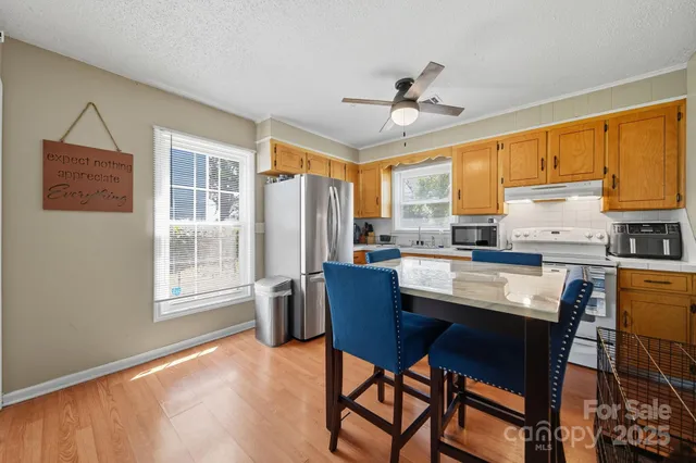 a kitchen with stainless steel appliances granite countertop white cabinets a refrigerator a stove a microwave oven with a dining table and chairs with wooden floor