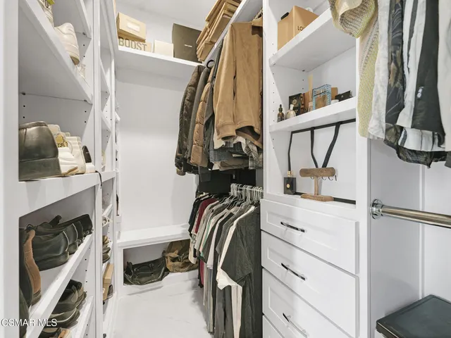a view of walk in closet with clothes and shoes