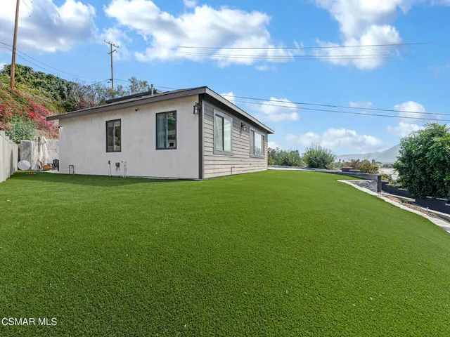 a view of a house with a yard and large tree