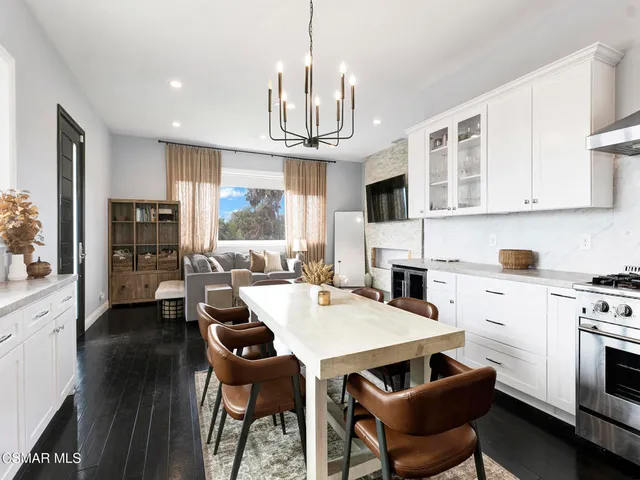 a open kitchen with stainless steel appliances granite countertop a stove a refrigerator a kitchen island a dining table and chairs with wooden floor