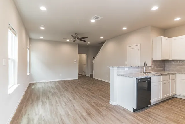 a view of a kitchen with kitchen island wooden floors granite counter tops and a window