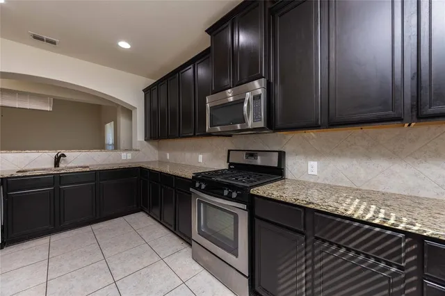 a kitchen with granite countertop a stove a sink and cabinets