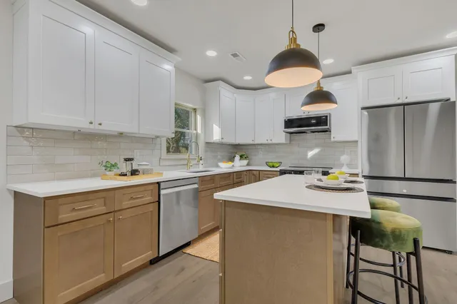 a kitchen with kitchen island granite countertop a sink a stove a refrigerator and white cabinets