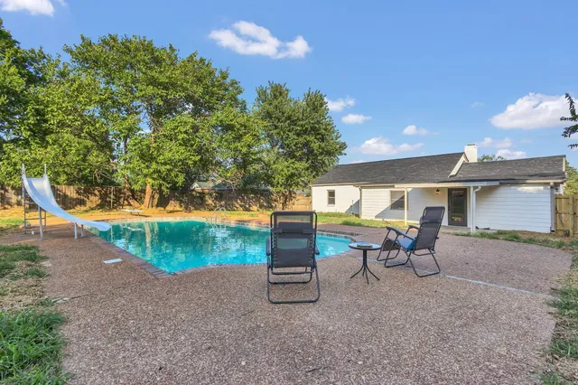 a view of a swimming pool with a yard and sitting area