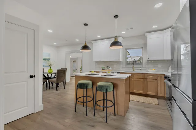 a large kitchen with kitchen island granite countertop a stove a sink a dining table and chairs with wooden floor