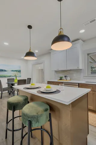 a kitchen with stainless steel appliances granite countertop a dining table chairs and white cabinets