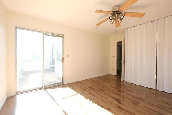 a view of an empty room and window with a ceiling fan