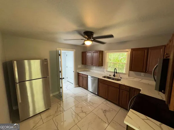 a kitchen with granite countertop a refrigerator a sink a stove and cabinets