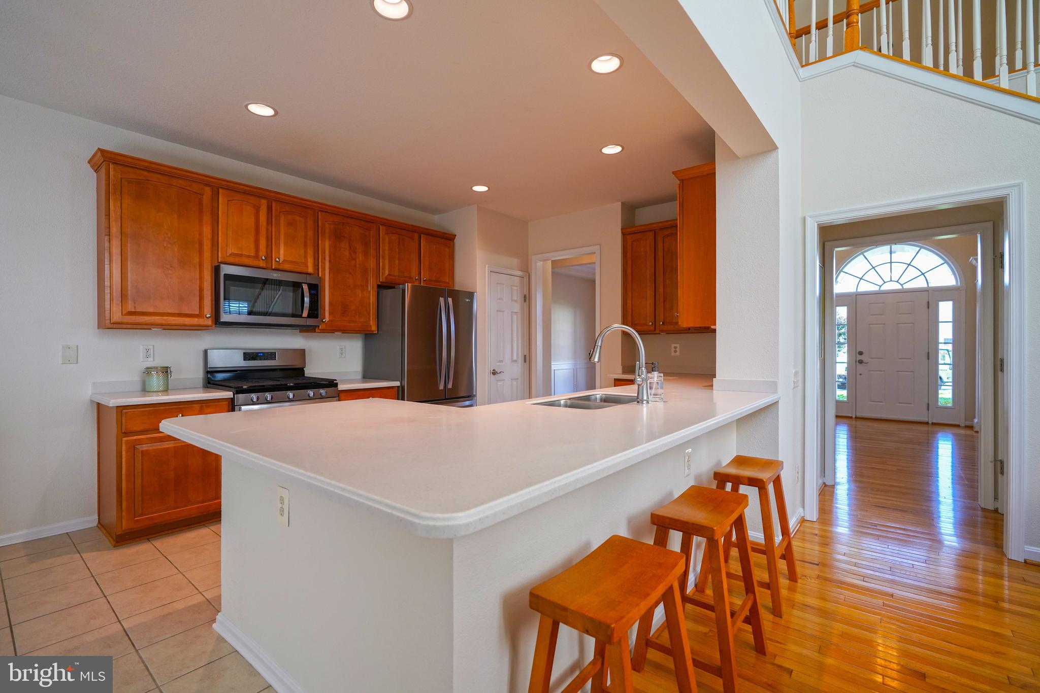 34953 Compass Cove Lewes, DE 19958 - Photo 18 of 90 a kitchen with stainless steel appliances granite countertop a sink a stove a refrigerator a microwave oven with a dining table and chairs