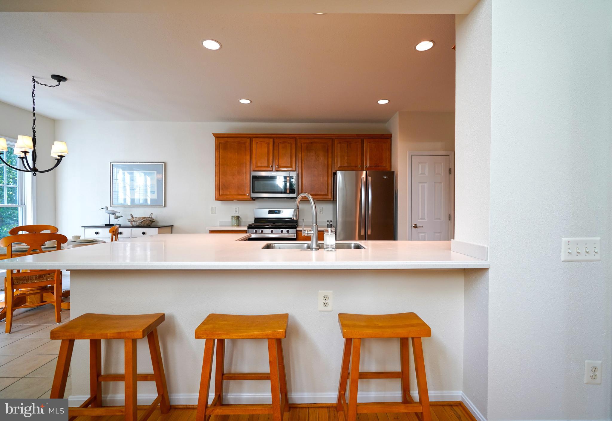 34953 Compass Cove Lewes, DE 19958 - Photo 19 of 90 a kitchen with stainless steel appliances a dining table chairs sink and cabinets