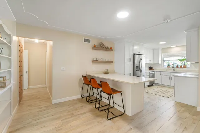 a kitchen with a dining table chairs refrigerator and cabinets