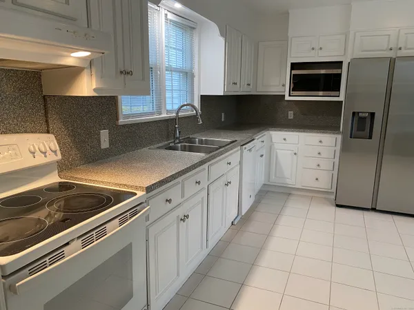 a kitchen with granite countertop white cabinets and stainless steel appliances