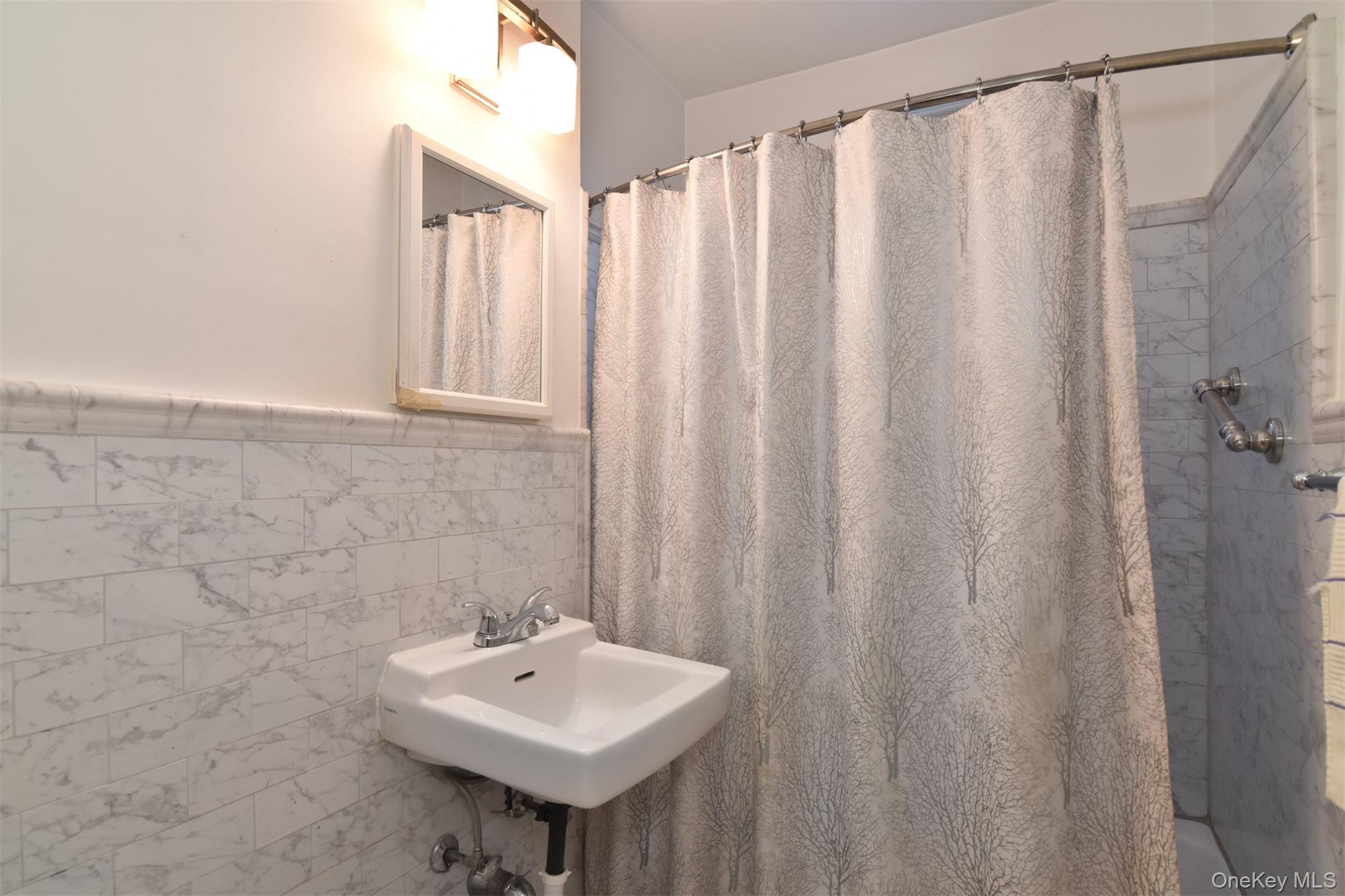 1 Georgia Avenue, Unit 3E Bronxville, NY 10708 - Photo 11 of 13 a bathroom with a sink a mirror and a shower curtain