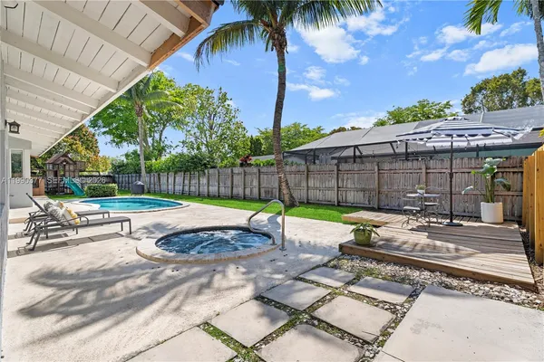 a view of a backyard with swimming pool and sitting area