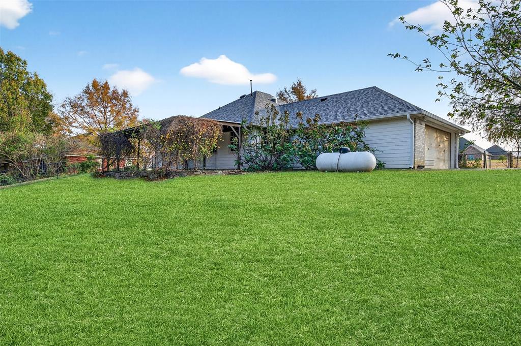 538 Lakewood Road Denison, TX 75020 - Photo 28 of 35 a house that is sitting in the grass with large trees and plants