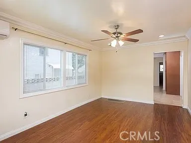 a view of an empty room with wooden floor and a ceiling fan