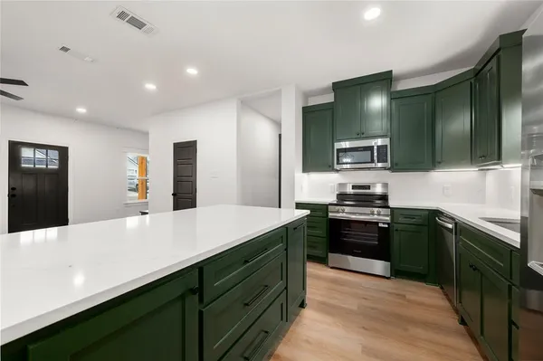 a kitchen with stainless steel appliances kitchen island granite countertop a refrigerator stove top oven and sink
