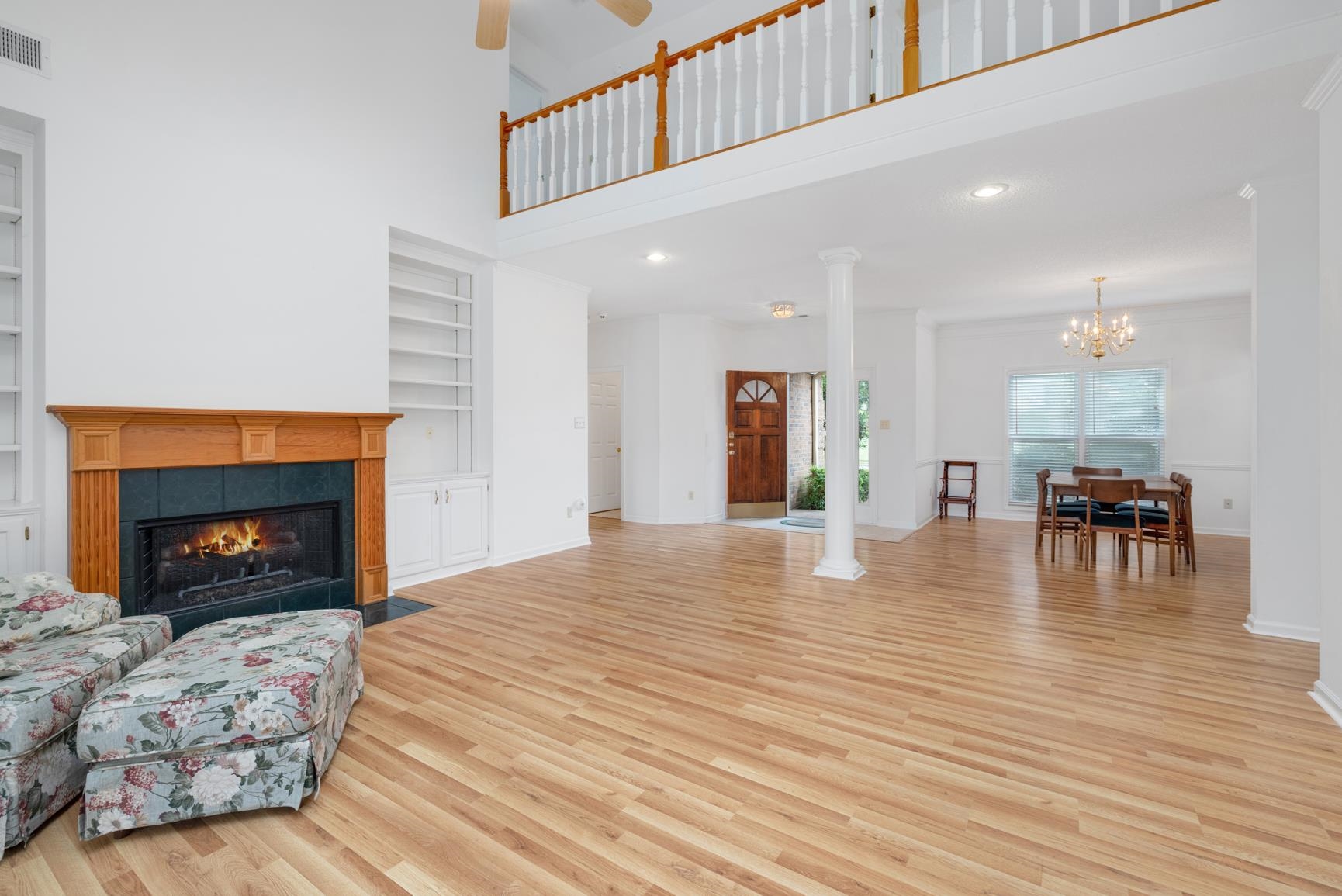9015 Raspberry Lane Cordova, TN 38016 - Photo 7 of 40 Living room featuring built in shelves, a fireplace, ceiling fan with notable chandelier, a towering ceiling, and light hardwood / wood-style floors