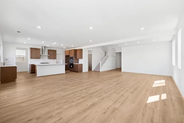 a view of kitchen with kitchen island a sink wooden floor and a refrigerator