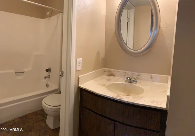 a bathroom with a granite countertop toilet a sink and a mirror