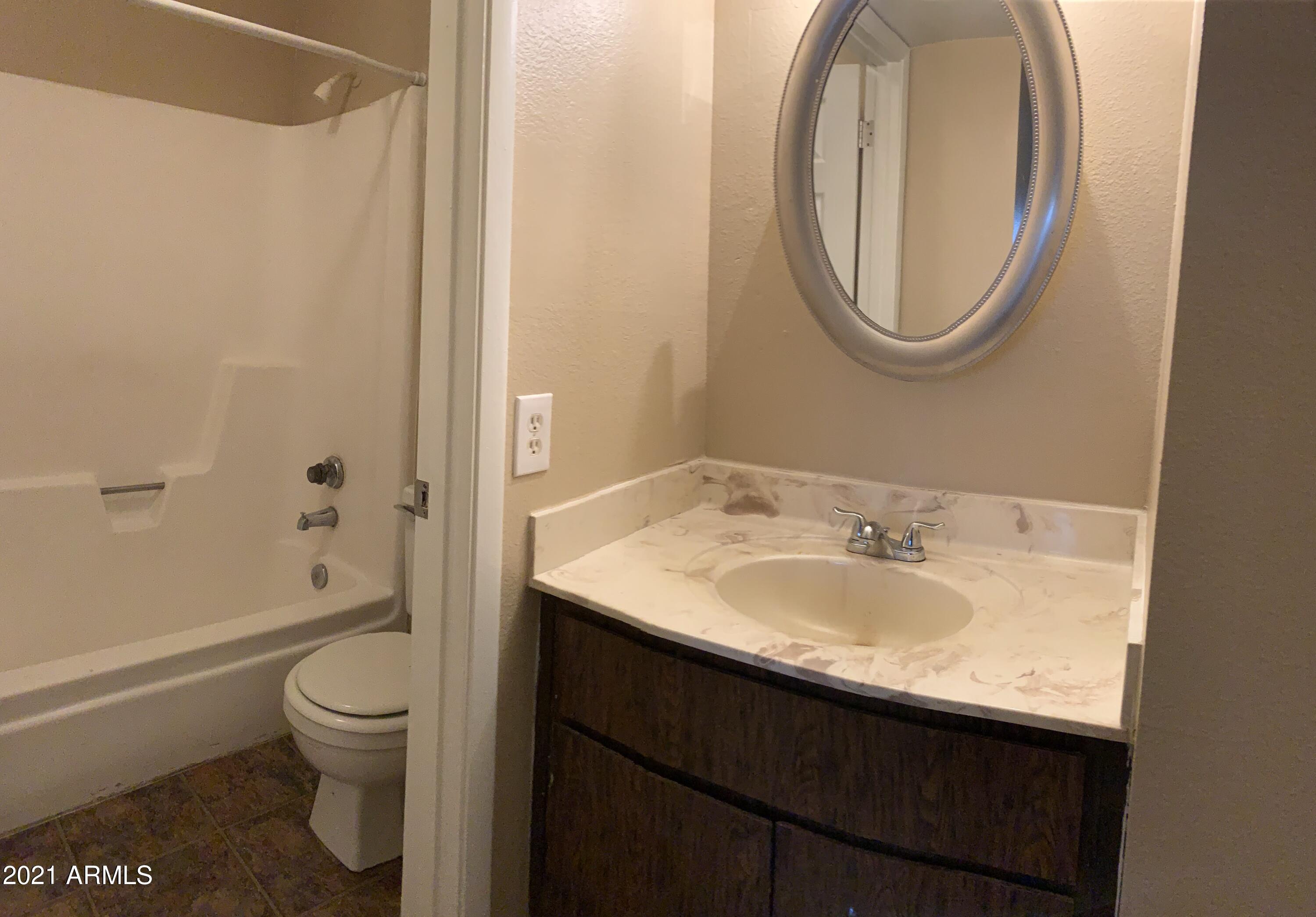 2217 East Cactus Road, Unit 4 Phoenix, AZ 85022 - Photo 12 of 14 a bathroom with a granite countertop toilet a sink and a mirror