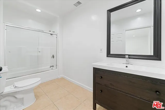 a bathroom with a toilet a sink a mirror and shower