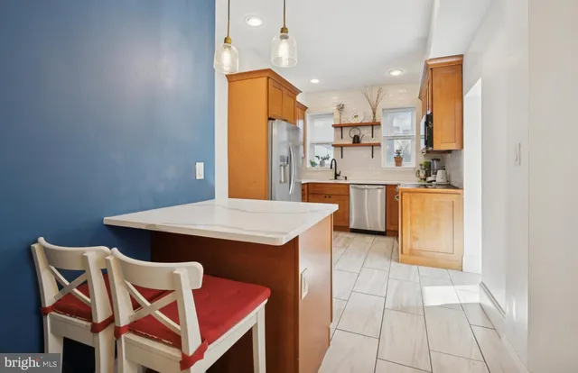 a kitchen with stainless steel appliances kitchen island granite countertop a table chairs in it and a microwave