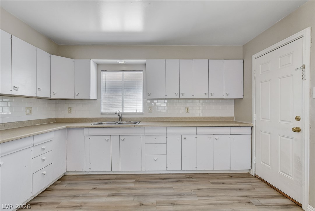 214 West Victory Road Henderson, NV 89015 - Photo 6 of 33 A well-appointed kitchen features ample white cabinetry, a sink below a window, and Luxury Vinyl flooring.