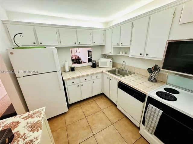 a kitchen with a sink a stove and white cabinets