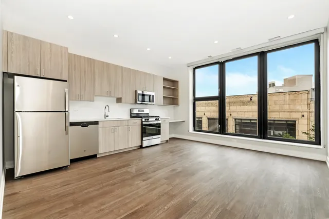a kitchen with stainless steel appliances a refrigerator sink and wooden floor