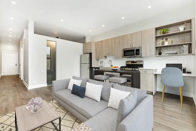 a living room with furniture a rug kitchen view and a window