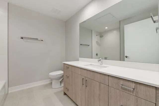 a bathroom with a granite countertop sink a toilet and a mirror
