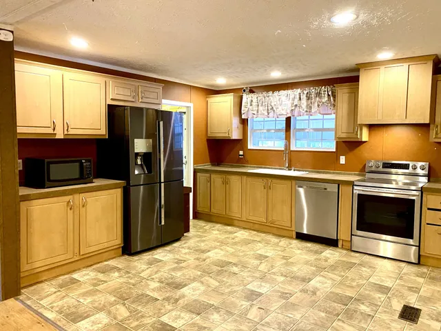 a kitchen with stainless steel appliances granite countertop a refrigerator and a stove top oven