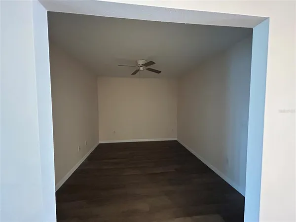 an empty room with wooden floor closet and windows