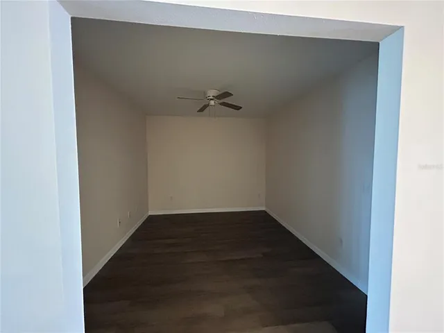 an empty room with wooden floor closet and windows