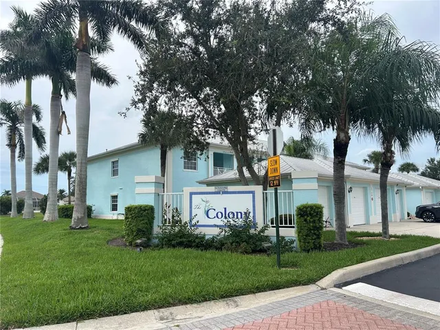 a view of a house with a yard and palm trees