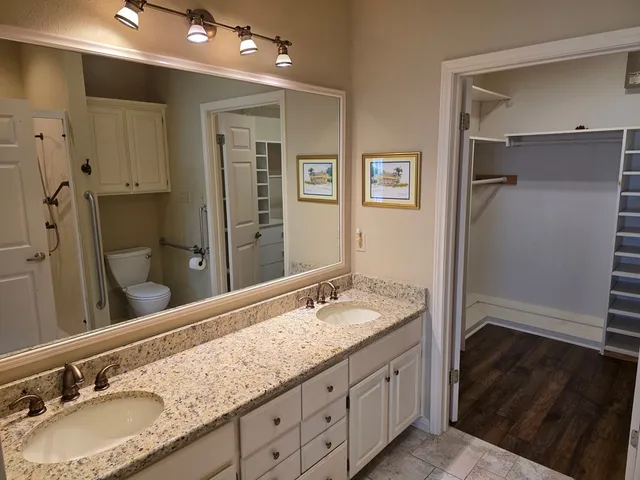 a bathroom with a granite countertop double vanity sink and mirror
