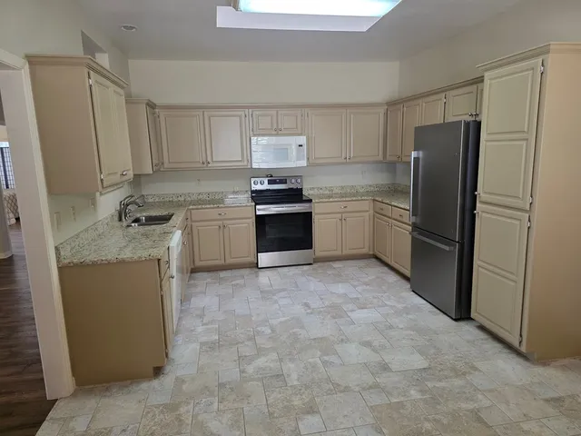 a kitchen with stainless steel appliances granite countertop a refrigerator sink and stove