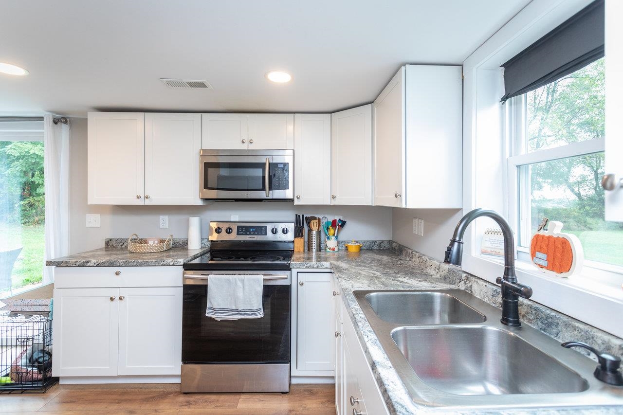 7452 Briery Branch Road Dayton, VA 22821 - Photo 15 of 66 a kitchen with white cabinets a sink a stove and a microwave