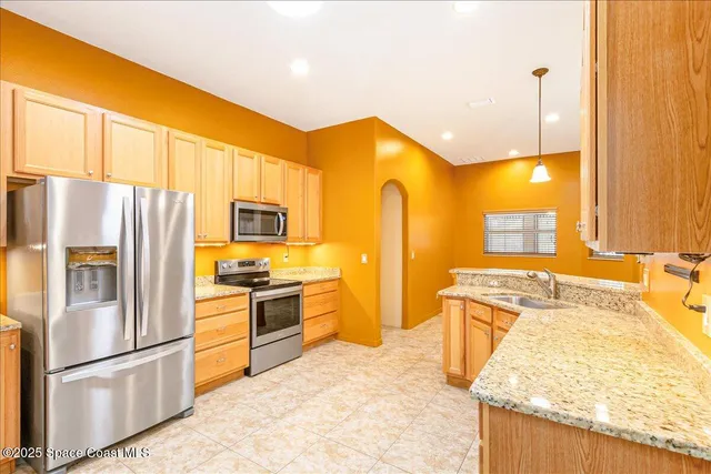 a kitchen with stainless steel appliances granite countertop a refrigerator a stove and a sink