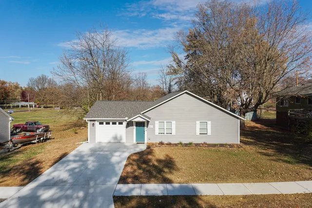 a view of a white house next to a yard and road