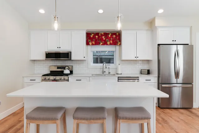 a kitchen with a refrigerator a stove a sink and white cabinets
