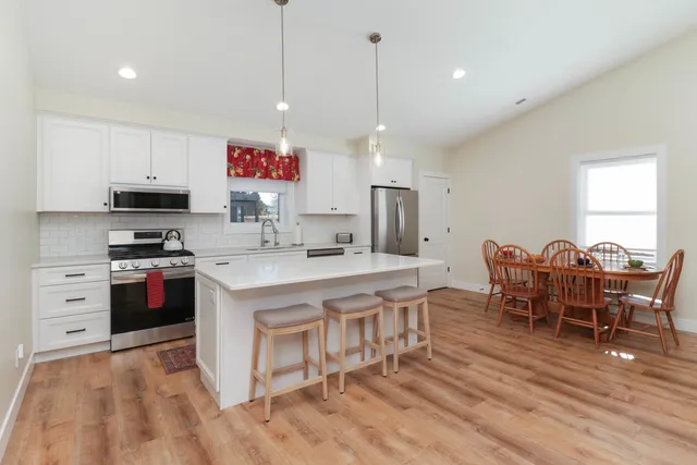 a large kitchen with stainless steel appliances granite countertop a stove a sink dishwasher a dining table and chairs with wooden floor