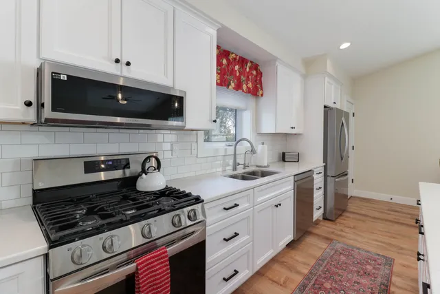 a kitchen with stainless steel appliances granite countertop a stove a sink and a microwave