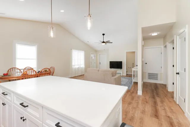 a large white room with a large bed a chandelier a mirror on the dresser and chandelier