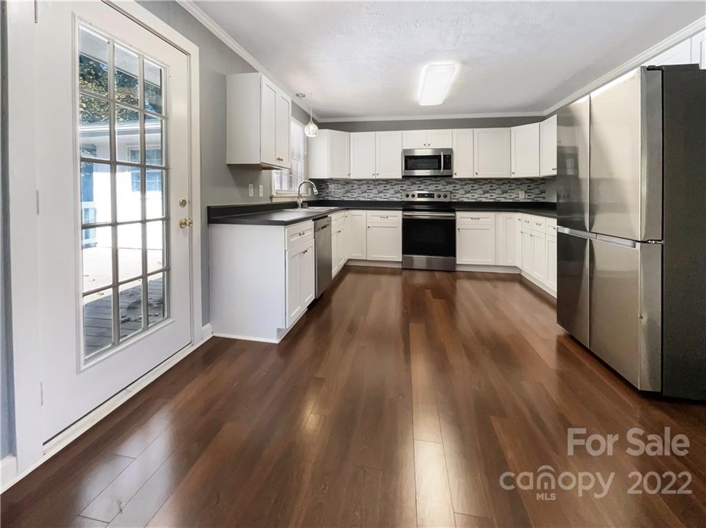 540 Neel Road Salisbury, NC 28147 - Photo 3 of 22 a kitchen with granite countertop a refrigerator a stove a sink and white cabinets with wooden floor