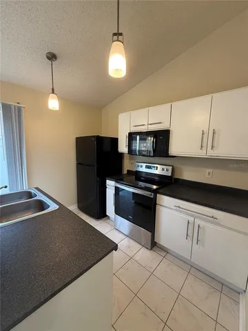 a kitchen with granite countertop a refrigerator and a stove top oven