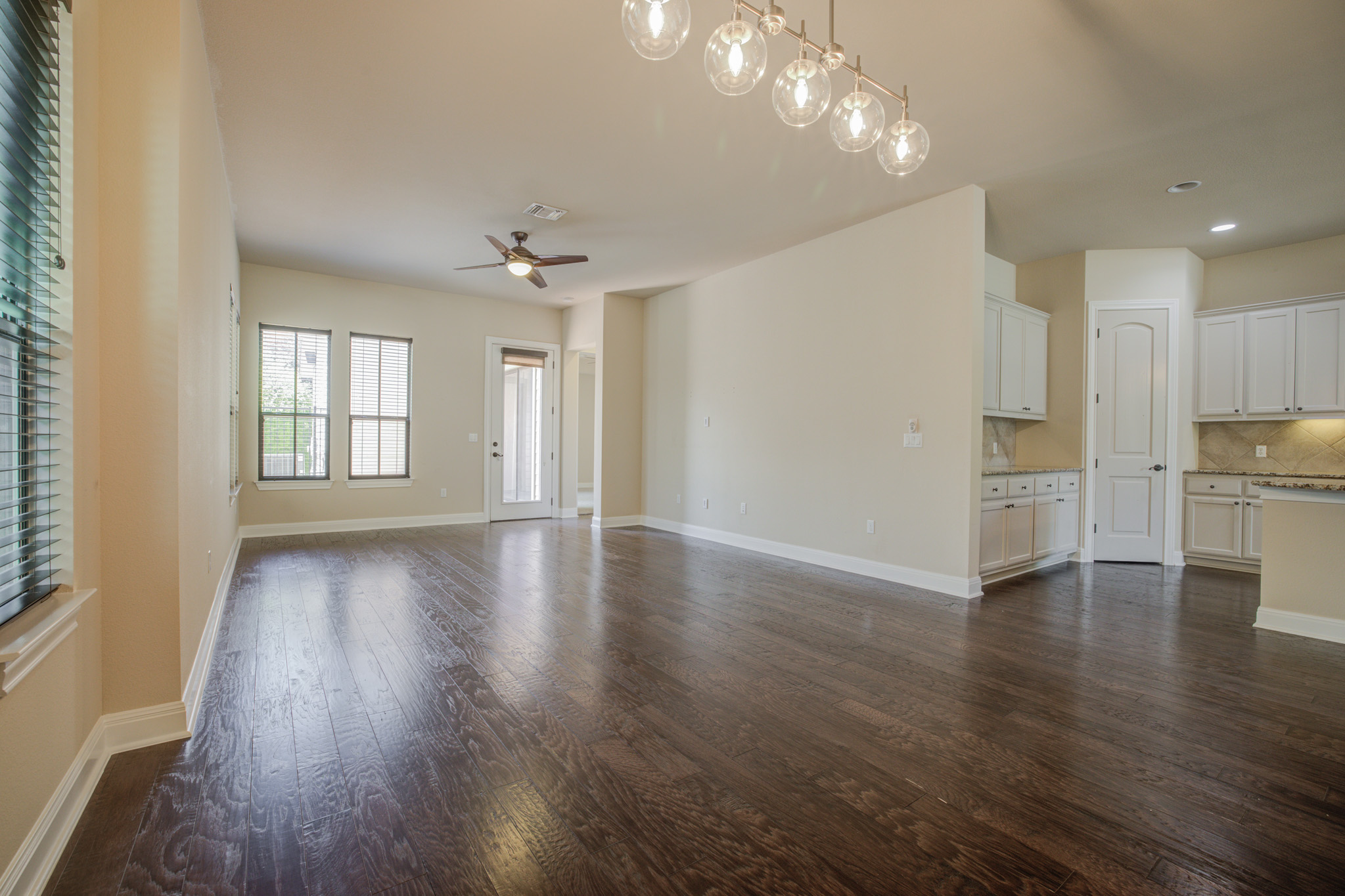 4524 Berkman Drive Austin, TX 78723 - Photo 16 of 38 Expansive living area featuring rich wood-finish flooring, multiple windows with blinds, and a contemporary linear chandelier
