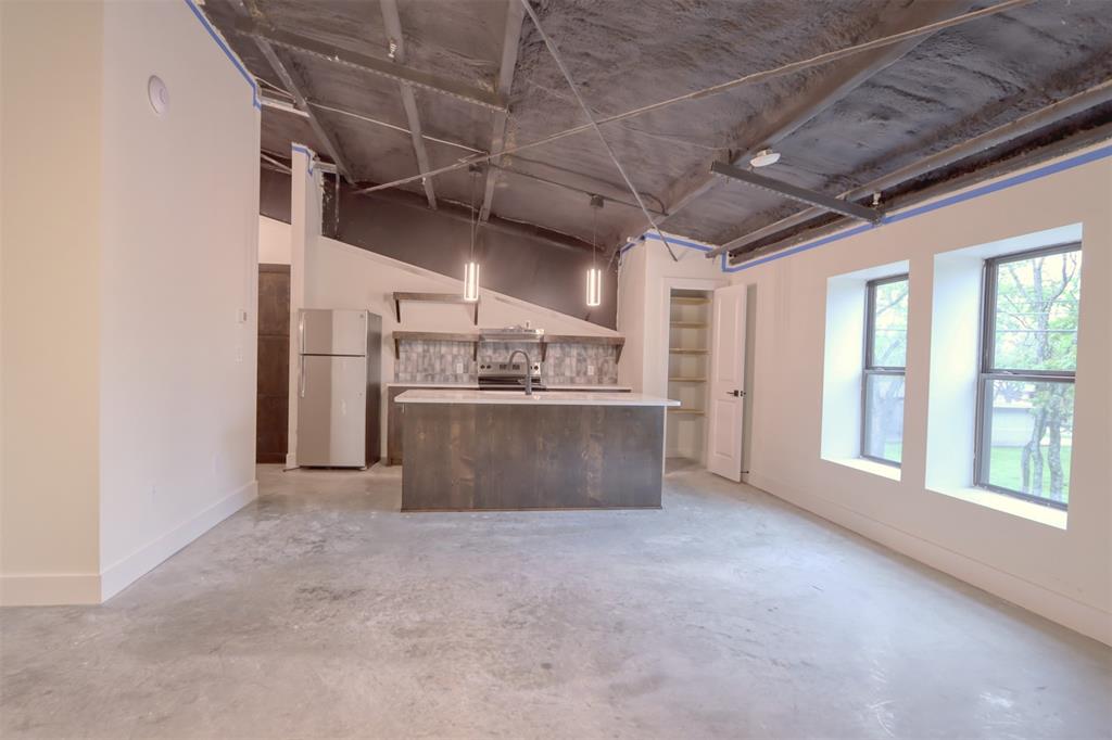 Unfurnished living room with unfinished concrete floors and a sink