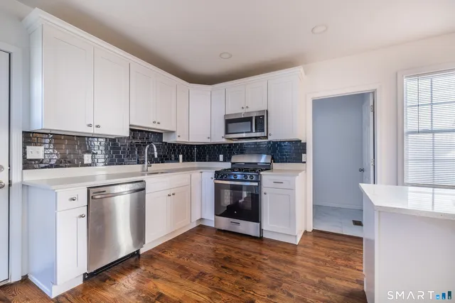 a kitchen with granite countertop white cabinets and stainless steel appliances